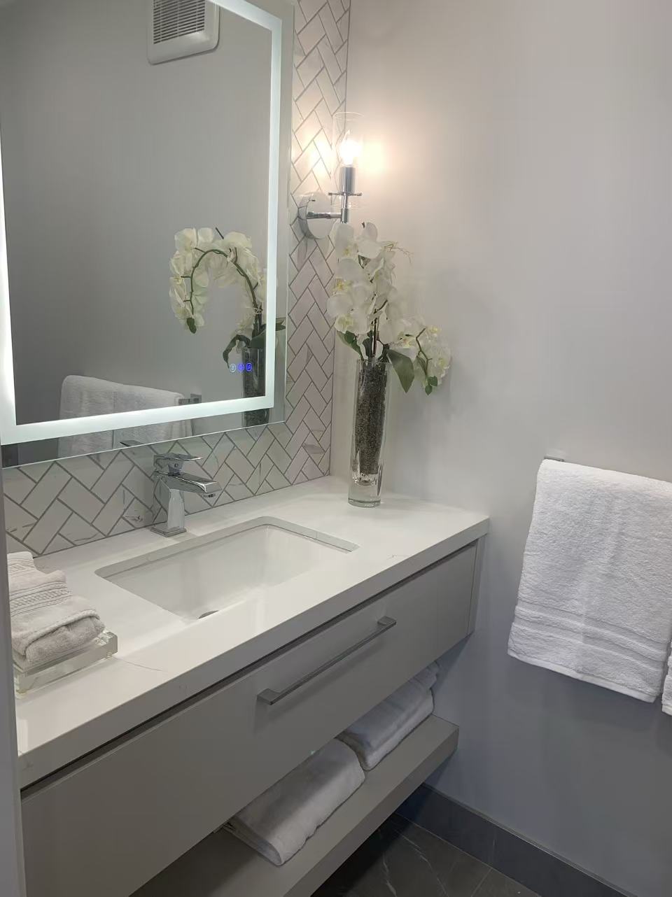White floating vanity herringbone tile